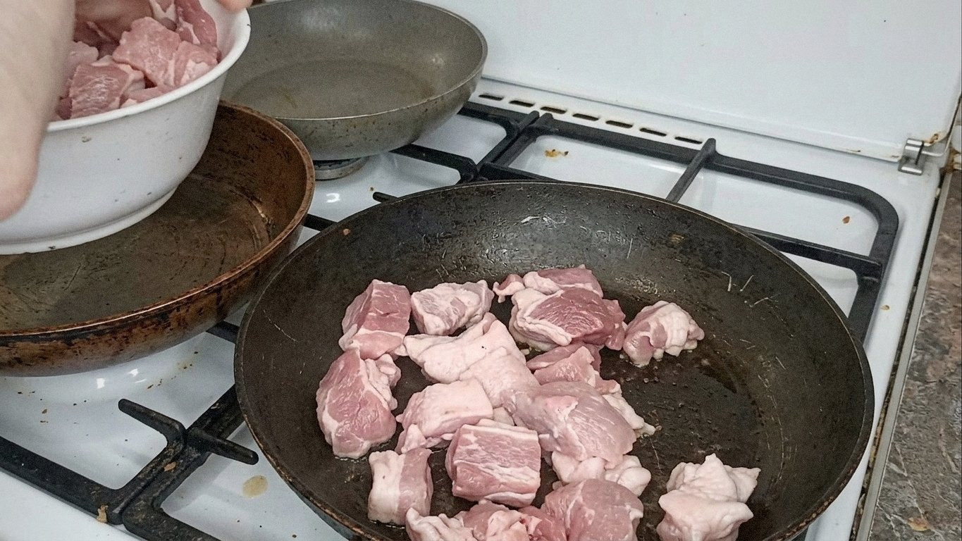 нарізане свиняче м'ясо, морква та цибуля на роздільній дошці
